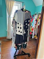 Full view of chrome clothing rack with garments (garments not included) on triangular base with casters