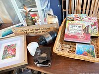 Overview of all items in lot including Kosta Boda votive, framed art pieces, basket, plaque, napkins, candle, figurine, bottle, tile