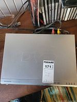 Top view of Magnasonic silver DVD player with cables and DVDs in background