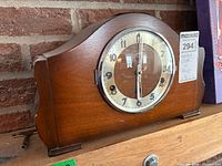 Front view of wood mantel clock showing glass bezel, dial, and key
