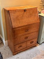 Front view of closed secretary desk showing three drawers and drop-leaf front