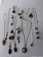 All jewelry pieces laid out: necklaces, earrings, pendants, ring