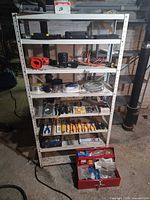 Full view of shelving unit with toolbox, drill, assorted tools