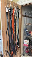 Multiple belts hanging on door showing variety of colors and materials