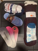 Assorted Sherpa slipper socks and Skechers liner socks displayed on black surface