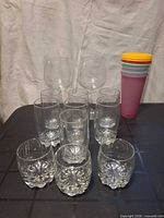 All glassware and plastic items grouped: wine glasses, tall tumblers, rocks glasses, plastic cups, lids