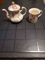 Teapot and cup side-by-side on table, shows overall style and relative size