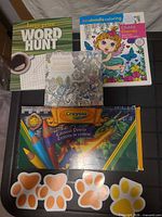 Overview of colored pencils box, three books and four paw sticky pads
