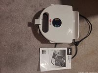 Top view of Salton SM-2 sandwich maker with attached power cord and accompanying instruction manual