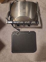 Closed Cuisinart Griddler with power cord and one plate beside unit