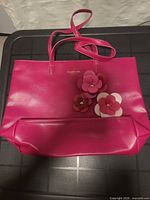 Front of fuchsia leather tote with floral appliqué and logo