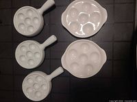 Top view showing all five white porcelain escargot dishes, three with handles, two without