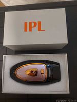 Device in foam inside box next to lid showing brand initials