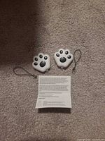 Front view of two paw-shaped trackers with manual and straps