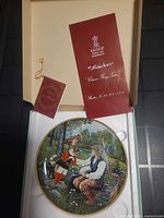 Open presentation box showing plate, certificate booklet, red insert, and stand