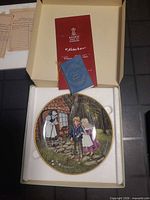 Open box showing porcelain plate, certificate booklet and stand