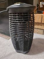 Full view of black cylindrical bug zapper showing grill and base