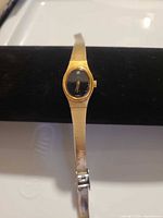 Lorus gold tone women's dress watch with black dial displayed on a bracelet holder