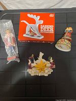 Overview of all four items: boxed deer nutcracker, wrapped wooden nutcracker, Santa bell, snowmen candle holder