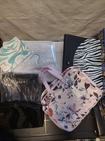 All five organizers grouped: floral bag, black roll-up, white hanging piece, zebra file, turquoise swirl bag