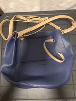 Front view of blue pebbled leather crossbody bag with tan strap and exterior pocket