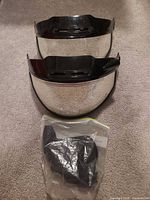 Two clear helmet visors stacked and sealed bag of mounting hardware
