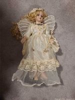 Full view of porcelain angel doll lying flat showing dress, wings, hair and facial details