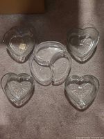 Five glass pieces: one tri-heart section dish and four heart bowls displayed on carpet