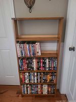 Full view of solid wood media shelf filled with DVDs and VHS tapes