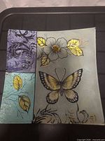 Front view of square glass plate showing butterfly, flower, leaves and color sections