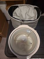 Top view of white Sunbeam slow cooker with glass lid alongside insulated travel bag