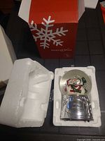 Snow globe in open styrofoam with box beside it