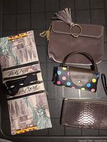 All four bags displayed flat: New York print organizer, grey velour clutch, polka-dot mini handbag, bronze snakeskin wristlet