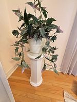 Full view of artificial plant in pot on ceramic pedestal