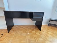 Front view of black desk showing drawers and panel sides
