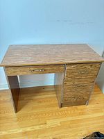 Front view of brown laminate desk showing drawers and handles