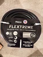 Coiled black Flexon Flextreme hose with packaging band visible