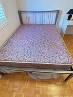 Full view of bed showing gray metal frame and mauve floral mattress