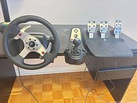 Wheel, shifter, and pedal set mounted on desk
