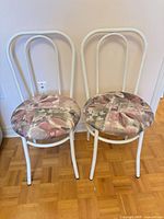 Front view of both white metal dining chairs
