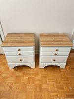 Front view of both nightstands showing white finish, drawer arrangement, natural wood knobs, arched base