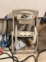 front view of beige plastic hose reel cart with hose, nozzle in tray