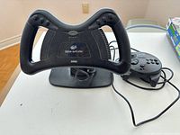 Front view of Sega Saturn steering wheel on base with controller and cables