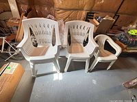 Three of the plastic patio armchairs side by side, showing overall design and discoloration