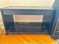 Front view of black MDF TV stand with open shelf and wheels