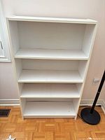 Front view of white 4-shelf bookcase showing overall structure and shelves