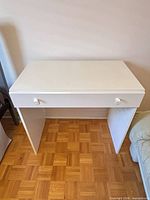 Front view showing desk, drawer, knobs and legs