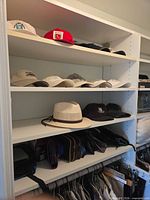 Shelves with multiple caps, straw hat, black crest hat and several small travel pouches