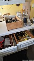 Open drawers and countertop showing knife block, three glass jars and assorted utensils