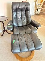 Full view of black leather swivel recliner showing seat, back, arms and wood ring base